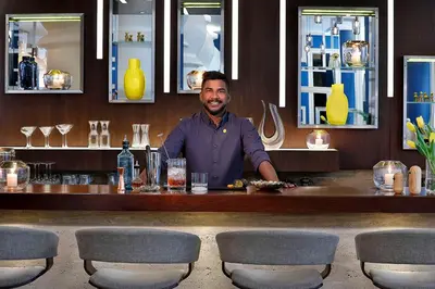a man standing behind a bar in a restaurant at voco Dubai by IHG in Dubai