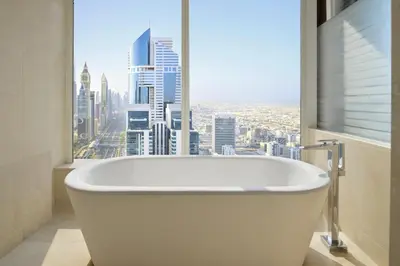 a bath tub in a bathroom with a large window at voco Dubai by IHG in Dubai