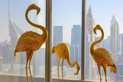 three wooden birds standing in front of a window at voco Dubai by IHG in Dubai