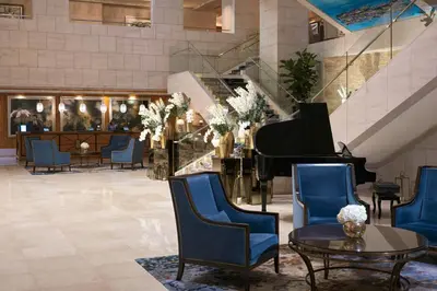 a lobby with a grand piano and blue chairs at Ritz Carlton DIFC Downtown Dubai in Dubai
