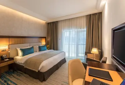 a hotel room with a bed and a desk and a television at Golden Tulip Media Hotel in Dubai