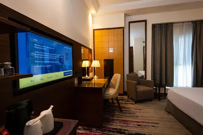 a hotel room with a bed and a flat screen tv at Golden Tulip Media Hotel in Dubai