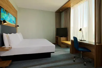 a hotel room with a bed and a desk and a television at Aloft Palm Jumeirah in Dubai