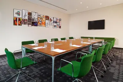 a conference room with a long table and green chairs at Aloft Me'aisam, Dubai in Dubai