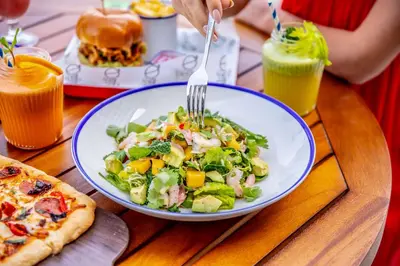 a plate of salad with a fork and a pizza at Rove Dubai Marina in Dubai