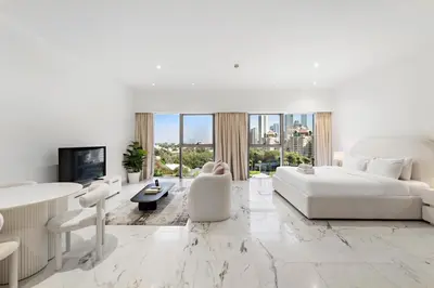 a white bedroom with a large bed and a living room at Studio Central Park DIFC in Dubai