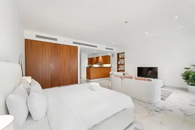 a white living room with white furniture and a tv at Studio Central Park DIFC in Dubai
