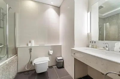 a white bathroom with a toilet and a sink at Studio Central Park DIFC in Dubai