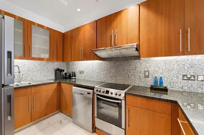 a kitchen with wooden cabinets and stainless steel appliances at Studio Central Park DIFC in Dubai