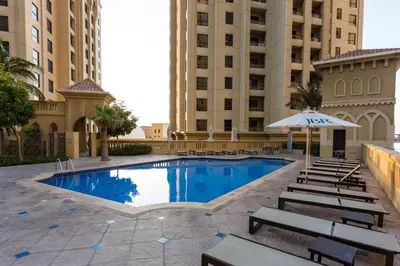 a swimming pool with benches and an umbrella next to buildings at ELAN Rimal 3 Suites in Dubai