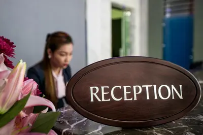 a sign that says reception on a table with flowers at Marina Byblos Hotel in Dubai