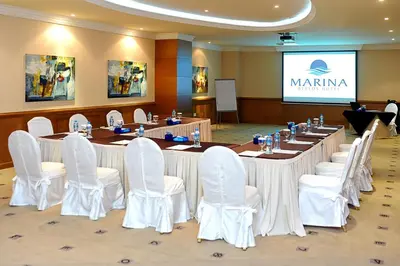 a conference room with a long table and white chairs at Marina Byblos Hotel in Dubai