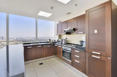 a kitchen with wooden cabinets and a large window at Nassima Tower Hotel Apartments in Dubai
