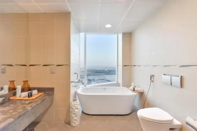 a bathroom with a tub and a toilet and a window at Nassima Tower Hotel Apartments in Dubai