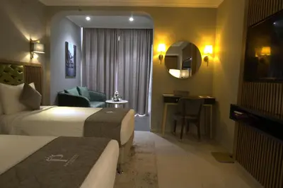 a hotel room with two beds and a desk at President Hotel in Dubai