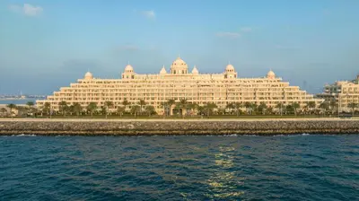 a large building sitting next to the water at Kempinski Hotel Palm Jumeirah in Dubai