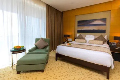 a bedroom with a large bed and a green chair at Westminster Dubai Mall in Dubai