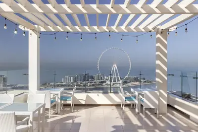 a patio with tables and chairs and a ferris wheel at Hilton Dubai The Walk in Dubai
