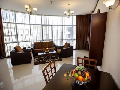 a living room with a table with a bowl of fruit on it at Xclusive Maples Hotel Apartment in Dubai