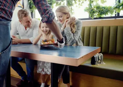 a man and two girls looking at a cake on a table at First Central Hotel Suites in Dubai