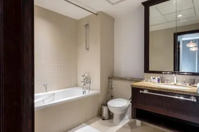 a bathroom with a tub and a toilet and a sink at Maison Privee - Exclusive Apt with Burj Khalifa Next Door in Dubai