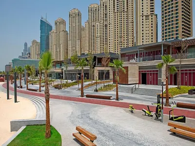 a park with benches and palm trees in a city at 2br Beach front Sea View in Dubai