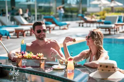 a man and a woman sitting at a table by a pool at Stella Di Mare Dubai Marina Hotel in Dubai