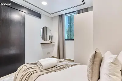 a white bedroom with a bed and a mirror at bnbmehomes - Gold Crest Views 2 in Dubai