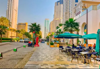 a sidewalk with tables and chairs and umbrellas on a city street at Murjan Suites Waterfront Jumeirah Beach Residence The Walk & Dubai Eye & Beach & Marina in Dubai