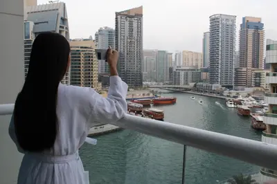 a woman taking a picture of a river from a balcony at Pearl Marina Hotel Apartments in Dubai