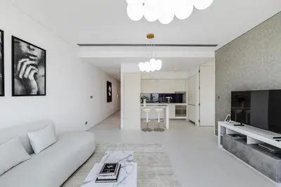 a white living room with a couch and a tv at 1BR Burj Khalifa View Index Tower DIFC in Dubai