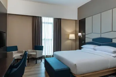 a bedroom with a large white bed and a desk at Four Points by Sheraton Production City, Dubai in Dubai