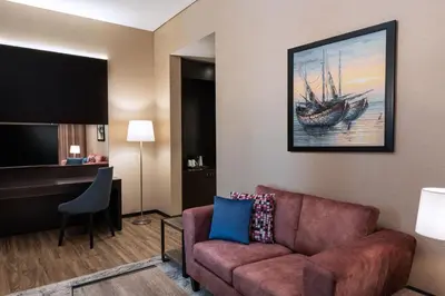 a living room with a couch and a painting of a boat at Four Points by Sheraton Production City, Dubai in Dubai