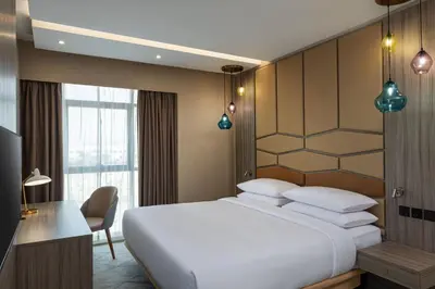 a bedroom with a large white bed and a desk at Four Points by Sheraton Production City, Dubai in Dubai