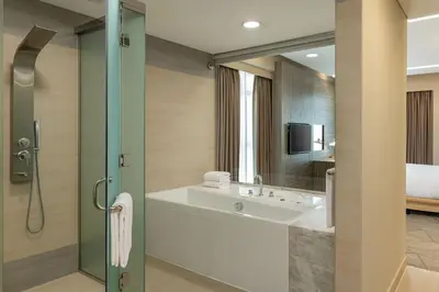 a bathroom with a tub and a sink and a bed at Four Points by Sheraton Production City, Dubai in Dubai
