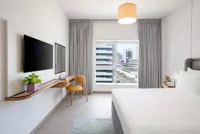 a hotel room with a bed and a desk and a window at Citadines Metro Central Dubai in Dubai