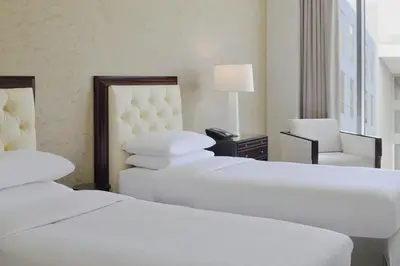 a hotel room with three beds and a chair at Delta Hotels by Marriott Dubai Investment Park in Dubai