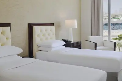 a hotel room with three beds and a chair at Delta Hotels by Marriott Dubai Investment Park in Dubai
