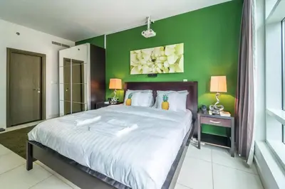 a bedroom with a large bed with a green wall at Divine Burj & Opera Views - 2BDR - DOWNTOWN DUBAI in Dubai