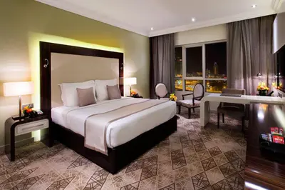 a hotel room with a large bed and a desk at Elite Byblos Hotel in Dubai