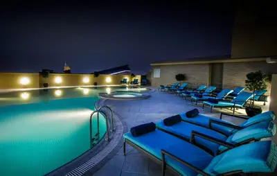 a swimming pool with blue lounge chairs next to it at Elite Byblos Hotel in Dubai