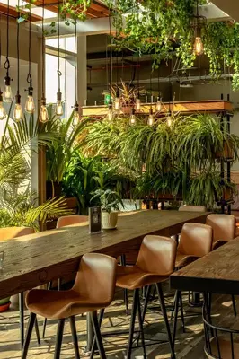 a large wooden table in a restaurant with plants at Zabeel House The Greens by Jumeirah in Dubai
