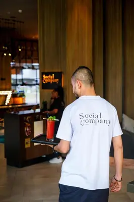 a man standing in a restaurant with a drink on a table at Zabeel House The Greens by Jumeirah in Dubai