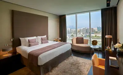 a hotel room with a large bed and a chair at The Canvas Dubai - MGallery Hotel Collection in Dubai