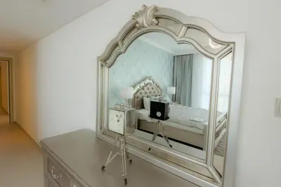 a bedroom with a large mirror on a dresser at Stunning 5* 4BR-Oceanfront-Apartment in Dubai