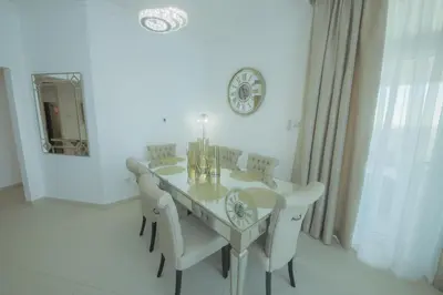 a dining room table with white chairs and a clock on the wall at Stunning 5* 4BR-Oceanfront-Apartment in Dubai