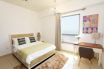 a bedroom with a bed and a desk and a window at Luxury Casa - Grand Sea View Apartment JBR Beach 2BR in Dubai