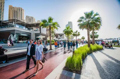a group of people walking down a sidewalk with palm trees at Luxury Casa - Grand Sea View Apartment JBR Beach 2BR in Dubai