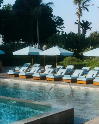 a group of lounge chairs and umbrellas next to a swimming pool at Delano Dubai at Bluewaters in Dubai