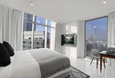 a white bedroom with a bed and a large window at Millennium Atria Business Bay in Dubai